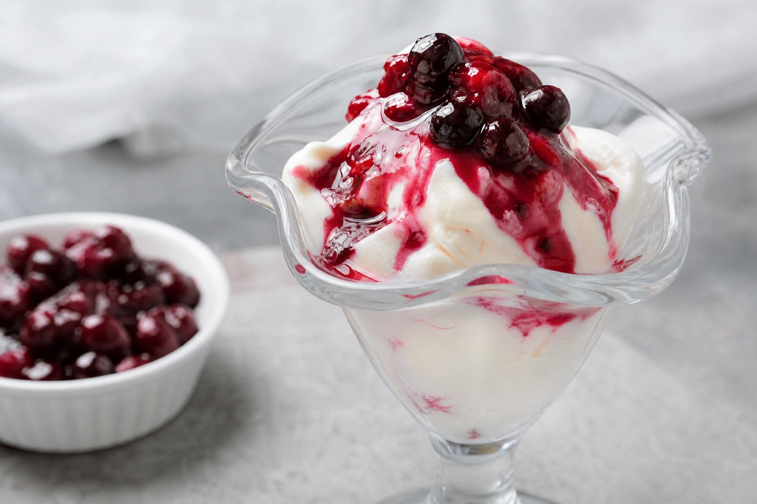 Sorvete de creme de iogurte cremoso com calda de frutas vermelhas em pote de sorveteria